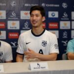 Heung-Min Son, wearing a Tottenham Hotspur jersey, waves to fans during a press conference in Seoul, with manager Thomas Frank seated beside him.