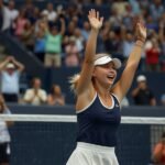 Amanda Anisimova raises her arms in triumph after defeating Naomi Osaka in a thrilling three-set match at the 2025 US Open semifinals in Arthur Ashe Stadium.