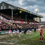 Red team plays while fans watch from packed stadium stands