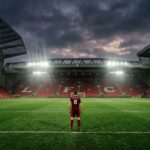 Player in maroon jersey standing alone on football pitch