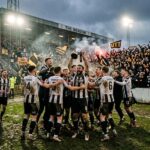 Football team celebrating trophy win with passionate crowd cheering
